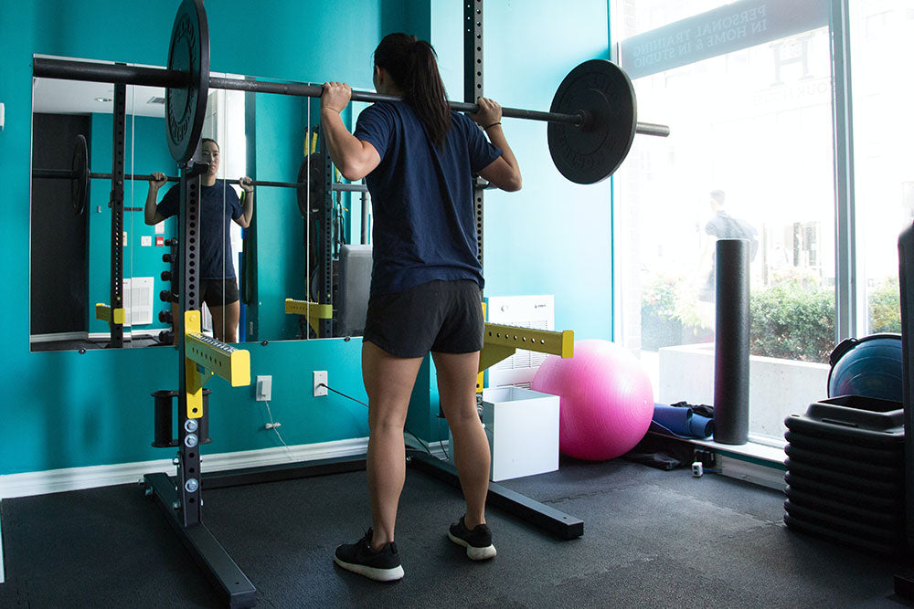 Girl using Squat Rack - Manic Fitness